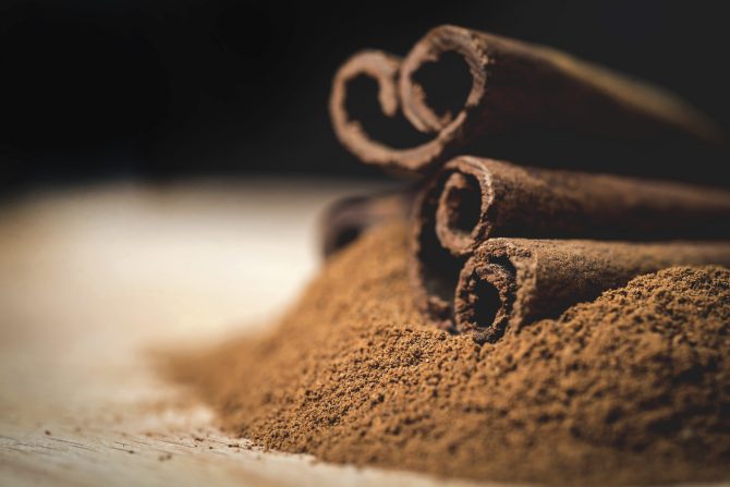 Cinnamon sticks with cinnamon powder on wooden background,